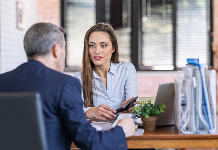 Woman talking to client at desk.