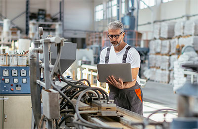 Man looking at his laptop in a manufacturing facility