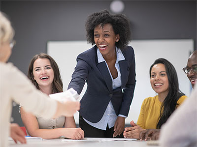 Businesswomen shaking hands across a table.