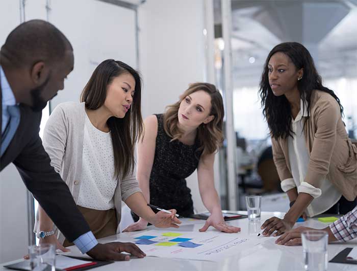 Four people standing at a work table.