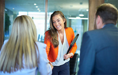 Woman shaking hands with two people sitting down.