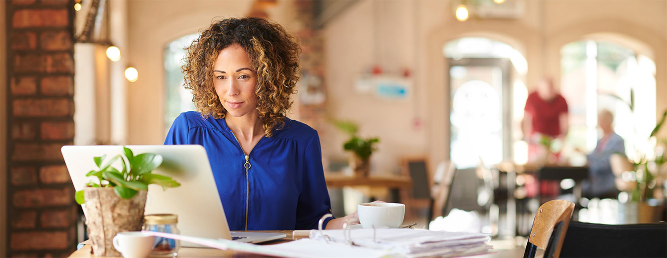 Woman sitting at a table using her laptop.